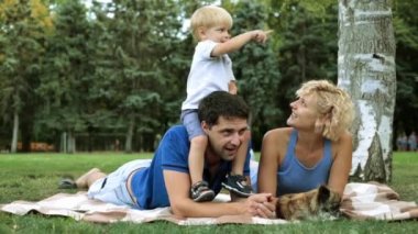 Aile piknik üzerinde bir çocukla. Baba, anne ve bebek bir ekose bir parkın içinde.