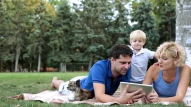 Aile piknik üzerinde bir çocukla bir tablet bilgisayar kullanın. Modern aile kavramı.