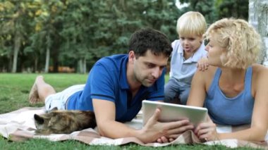 Bir çocuk ile anne bir tablet bilgisayar kullanın. Bir piknik bir çocuk ile aile.