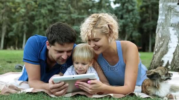 Сім'я з дитиною на пікніку використовує планшетний комп'ютер. Поняття сучасної сім'ї . — стокове відео