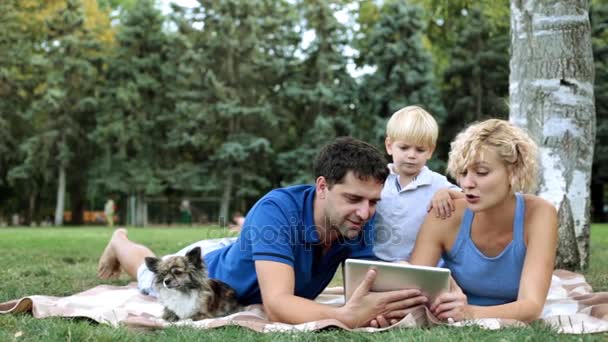 Familia con un niño en un picnic use una tableta . — Vídeos de Stock