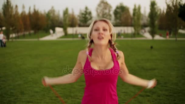 Mooie jongedame is springtouw. De sporter is betrokken bij de fitness in het park. — Stockvideo