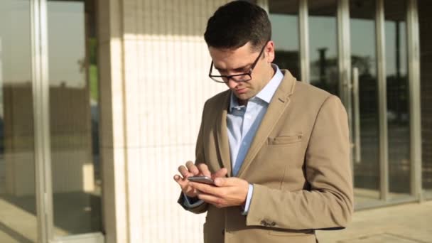 Biznesmen z smartphone na tle budynku biurowego. — Wideo stockowe