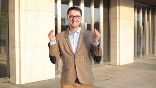 Jonge succesvolle zakenman dansen op de achtergrond van een kantoorgebouw. — Stockvideo