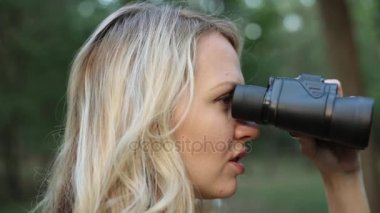 Genç bir kadın dürbün ile görünüyor. Dürbün, kızla yakın çekim.