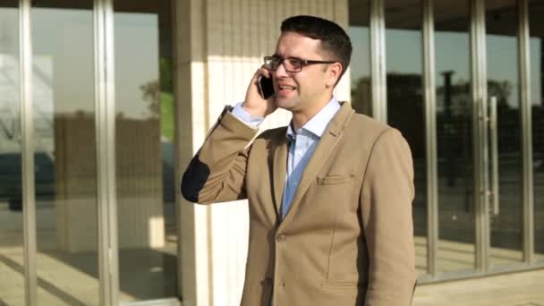 Бізнесмен розмовляє по телефону на фоні офісної будівлі . — стокове відео