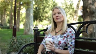 Genç çekici kadın bankta kahve içiyor.