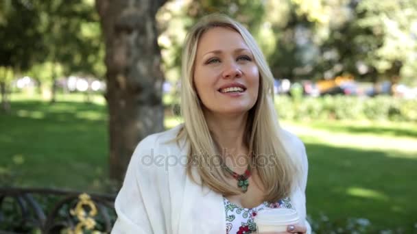 Beautiful woman is walking outdoors and drinking coffee or tea. — Stock Video