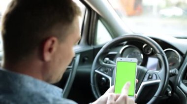 Arabada bir işadamı bir akıllı telefon ile yeşil bir ekran kullanır..