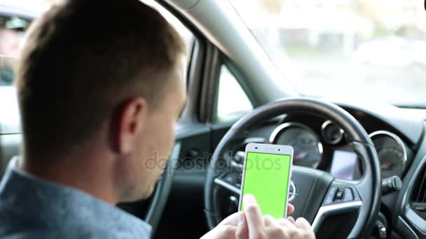 Homem no carro usa um smartphone com uma tela verde . — Vídeo de Stock