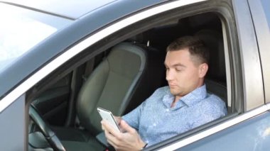 Bir araba bir işadamı bir smartphone kullanarak bir ileti yazar.