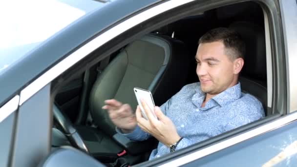 En affärsman i bilen använder en smartphone. En man med en smartphone i bilen. — Stockvideo