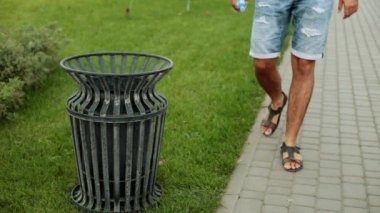 Bir adam çöp bir sokak çöp kutusuna atar..