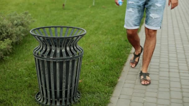 Een man gooit vuilnis in een straat Prullenbak. — Stockvideo