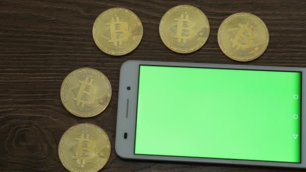 Zlatý bitcoiny a smartphone s zeleným plátnem pro svůj obsah. — Stock video