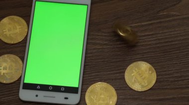 Bitcoins ve yeşil bir ekran ile smartphone.