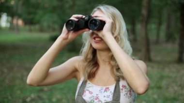 Dürbün ile ormanın içinde bir kadın görünüyor.