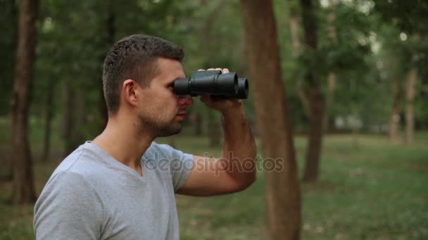 A man with binoculars in the woods. — Stock Video