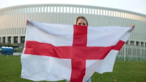 Egy nő, egy nagy zászló az angol. Foci rajongó Anglia ellen a háttér, a stadion. — Stock videók