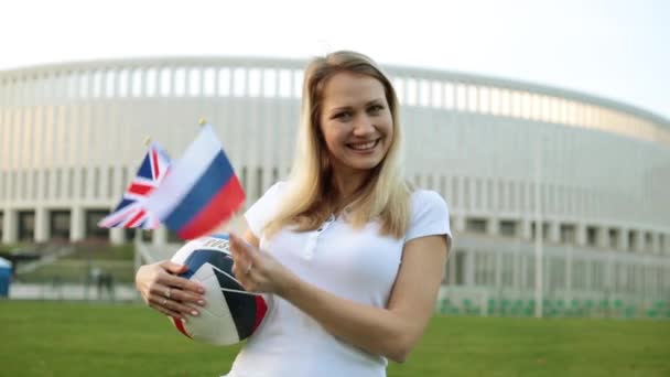 Een vrouw met een voetbal bal zwaaien de vlag van Rusland en Groot-Brittannië. — Stockvideo