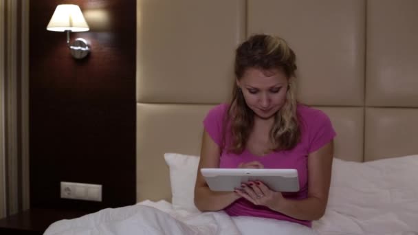 Vrouw met een tablet-pc op het bed. — Stockvideo