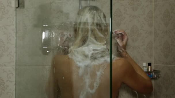 Uma mulher a lavar-se no chuveiro. A menina toma um banho . — Vídeo de Stock