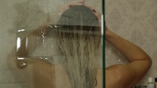 Una mujer se lava la cabeza en la ducha . — Vídeos de Stock