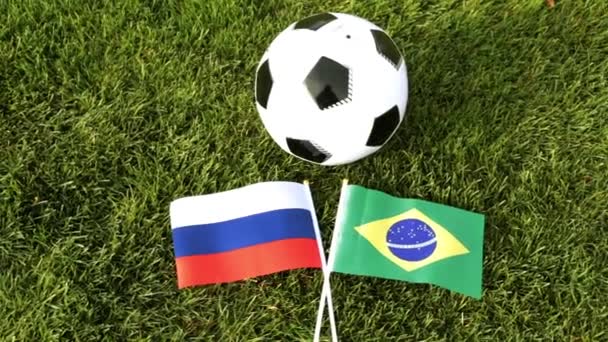 Fotbalový míč a vlajky Ruska a Brazílie. Fotbalový míč v trávě, světový pohár. — Stock video