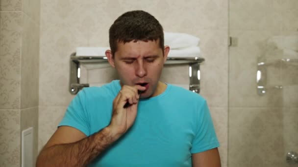 En sömnig man borstar sina tänder i badrummet. — Stockvideo