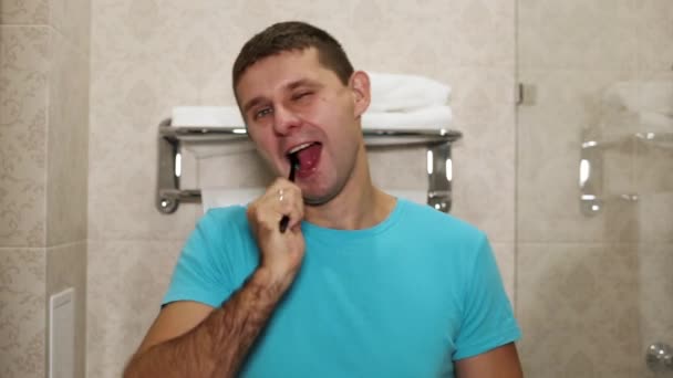 Ένας άνθρωπος βουρτσίζετε τα δόντια του στο μπάνιο. — Αρχείο Βίντεο