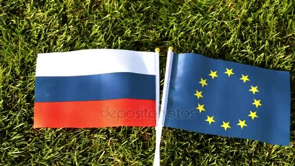 Vlajky Ruska a Evropské unie na zelené trávě. — Stock video
