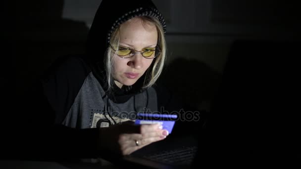 Un hacker con un portátil y una tarjeta bancaria . — Vídeo de stock