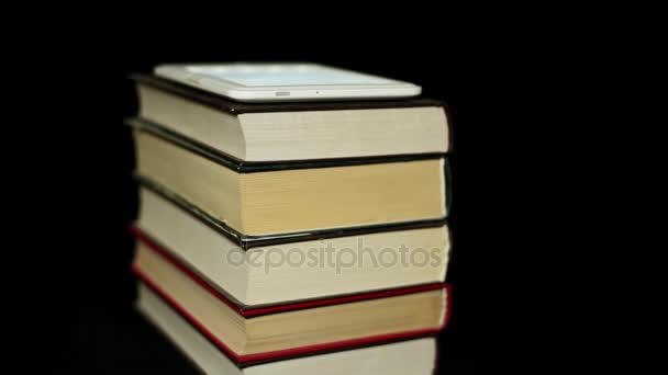纸质书籍和电子书。黑色背景下的阅读器和书籍. — 图库视频影像