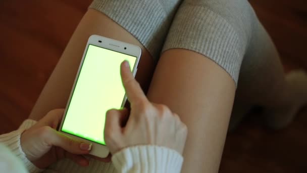 Una mujer sostiene un teléfono inteligente con una pantalla verde. Un smartphone con pantalla verde para tu contenido . — Vídeos de Stock