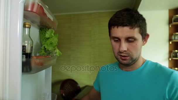 Чоловік відкриває холодильник. Чоловік виймає курку з холодильника . — стокове відео