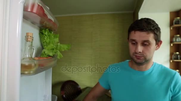 Un uomo in cucina apre il frigo. Un uomo prende la carne dal frigorifero . — Video Stock