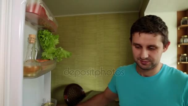 Um homem na cozinha abre o frigorífico. O homem tira a fruta do frigorífico. . — Vídeo de Stock