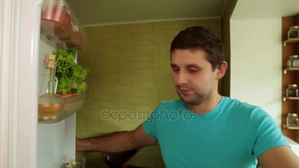 Człowiek wyjmuje pomarańcze z lodówki. Człowiek w kuchni otwiera lodówkę. — Wideo stockowe
