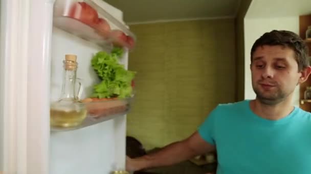 Un uomo tira fuori ananas e banane dal frigorifero. Un uomo in cucina apre il frigorifero . — Video Stock
