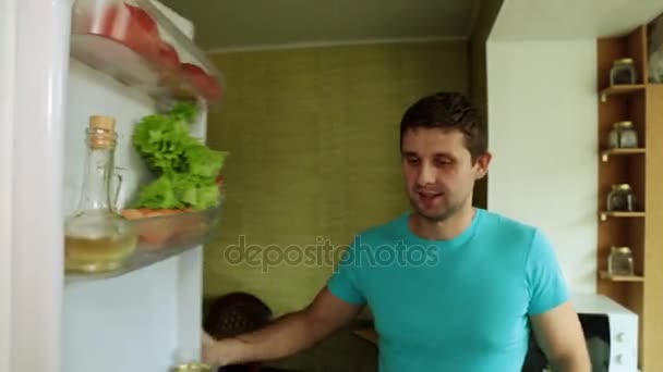 Ένας άνθρωπος παίρνει ένα πορτοκάλι και το χυμό από το ψυγείο. Ο τύπος στην κουζίνα, ανοίγει το ψυγείο. — Αρχείο Βίντεο