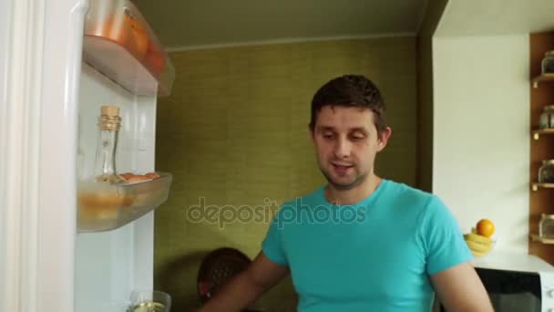 Un hombre saca verduras frescas del refrigerador. Un vegetariano abre el refrigerador en la cocina . — Vídeos de Stock