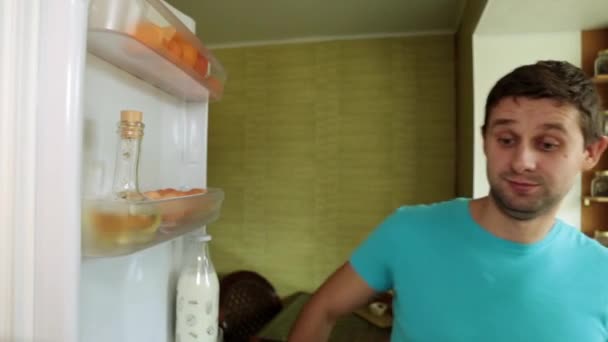 Чоловік відкриває холодильник і виймає сік. Чоловік вливає сік у склянку на кухні . — стокове відео
