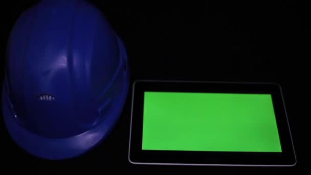 Een tablet met een groene display en een helm bouw. — Stockvideo