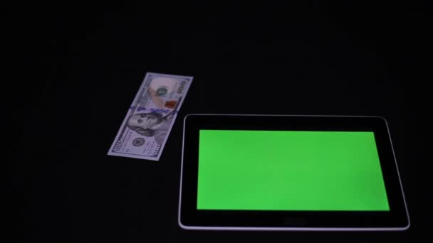 Surfplatta med en grön skärm och amerikanska dollar. TabletPC och dollar. — Stockvideo