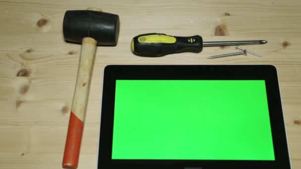 Hulpprogramma's en een tablet met een groene display. Hamer, schroevendraaier en Tablet PC-computer. — Stockvideo