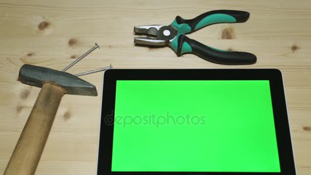 Tangen, hamer en tablet met een groen scherm. Handgereedschappen en een tablet. — Stockvideo