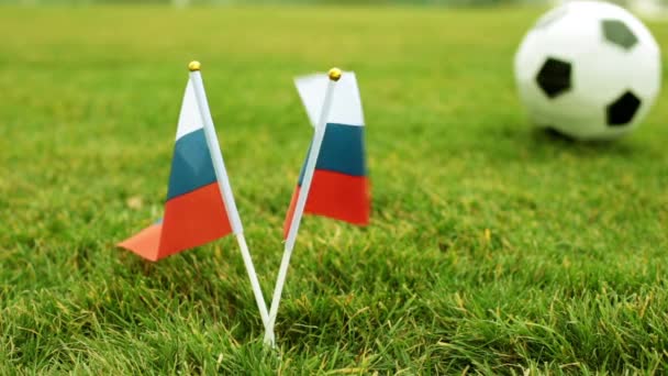 Bandeira da Rússia e bola de futebol. Bandeiras da Federação Russa em grama verde e uma bola de futebol . — Vídeo de Stock