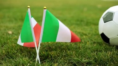 Çimenlerin üzerinde İtalyan bayrağı ve futbol topu.