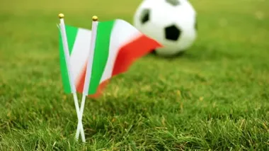 İtalyan bayrağı arka planda bir futbol topu. Çimenlerin üzerinde İtalyan bayrağı ve futbol topu