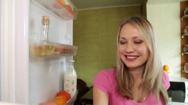 Жінка відкриває холодильник, виймає сік і п'є . — стокове відео